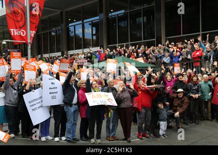 Protesters in Martin Place, Sydney say ‘hands off the ABC’ as they pose for a group photo taken from above in the shape of the ABC logo. Stock Photo