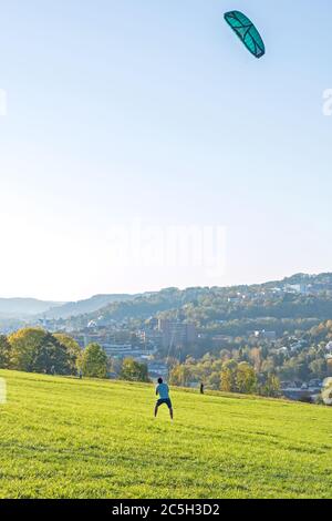 Man is steering big kite on a green meadow Stock Photo