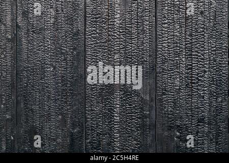 Charred black wooden wall with copy space. Abstract background with a burned boards textures closeup Stock Photo
