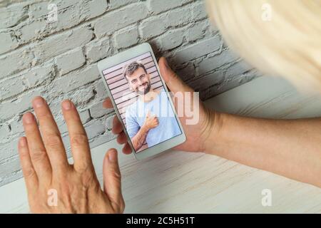 Smartphone video call to talk to son. Mother connecting with her son during quarantine. Guy making video call to mom. Mother and son online Stock Photo