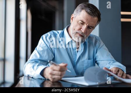 Businessman sitting in a business center restaurant, looking through contract. Stock Photo