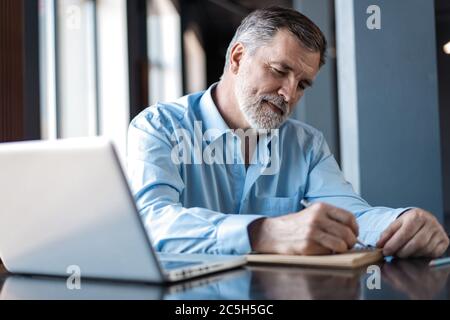 Businessman sitting in a business center restaurant, looking through documents. Stock Photo