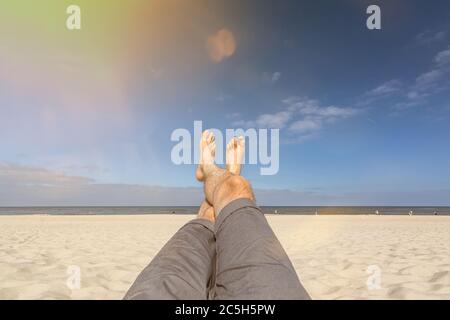 Selfie shot of legs and feet while relaxing on a beautiful beach in summer with scenic lens flare Stock Photo