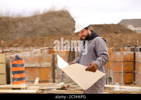 Male foreman looking at drawing plan of hause at construction site. Stock Photo