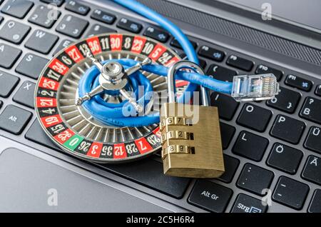 Roulette wheel, padlock and internet cable lying on computer keyboard symbolizing data encryption Stock Photo