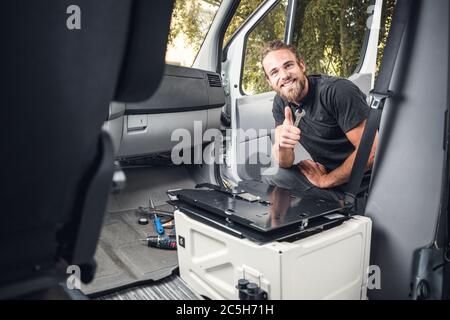 Smiling man working inside his camper van Stock Photo