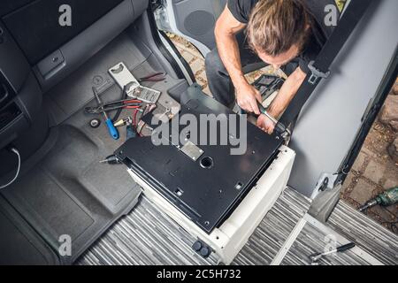 Man installing a swivel seat base in his camper van Stock Photo