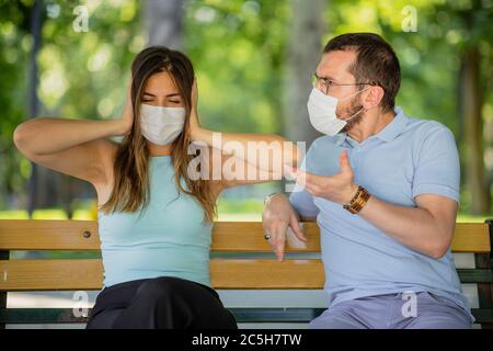 New normal concept after the pandemic an arguing couple view, man is dictating, woman close ears and unconcerned, they are wearing a mask Stock Photo