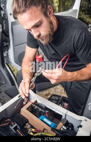 Man working on electronics inside his camper van Stock Photo