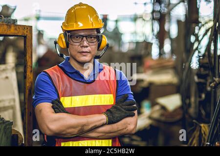 Asian Professional worker standing arm cross in heavy industry working in factory production line process with eyes and ears safety. Stock Photo