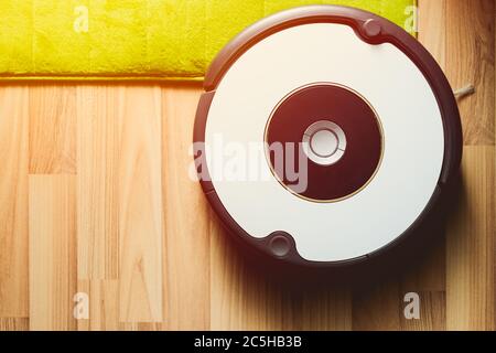 Robot vacuum cleaner on laminate wood floor with carpet cleaning Stock Photo