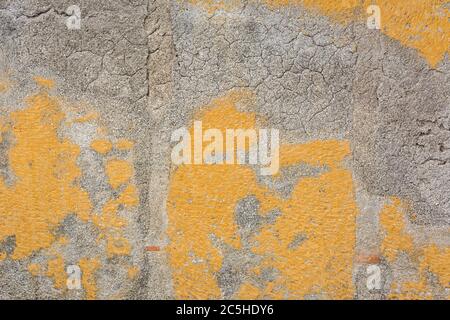 Background weathered concrete wall with partly peeled off yellow paint Stock Photo