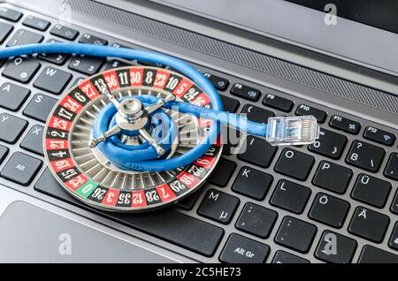 Roulette wheel and internet cable lying on computer keyboard symbolizing data encryption Stock Photo