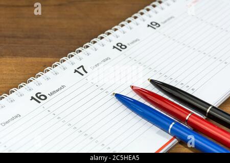 Three pens lying on schedule (with captions of the days of the week in German) Stock Photo