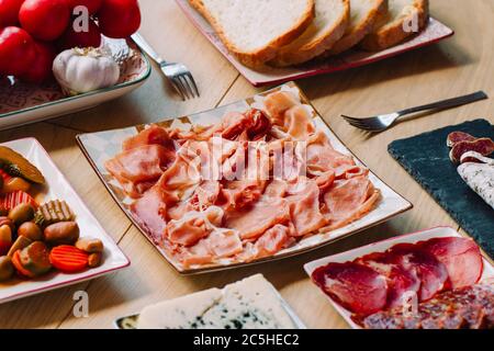 Spanish serrano ham on a table, with pa amb tomaquet (translated as bread with tomato) and garlic Stock Photo