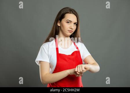 Portrait of female supermarket employee making late gesture on gray background Stock Photo