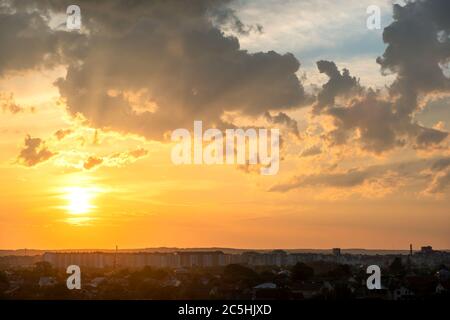 Dramatic sunset over rural area with puffy clouds lit by orange setting sun and blue sky. Stock Photo