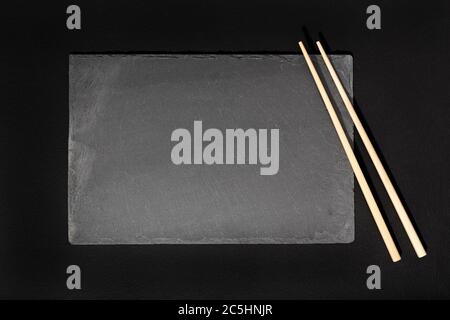 Empty Black slate Tray Plate and chopsticks on black background. Top view Mock up Stock Photo
