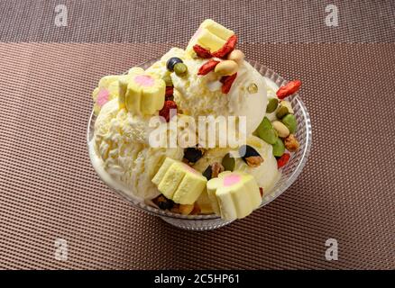 side view bowl of vanilla flavor ice cream balls with marshmallows and various nuts Stock Photo