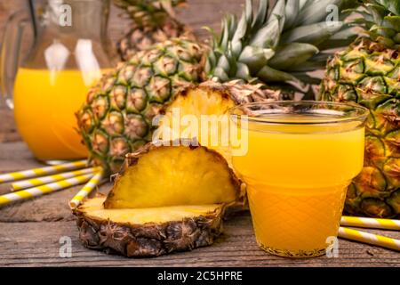 The glass of pineapple juice with pieces of pineapple. Fruit ocktail on rustic wooden table.Detox and an antioxidant drink. Healthy drink concept. Stock Photo