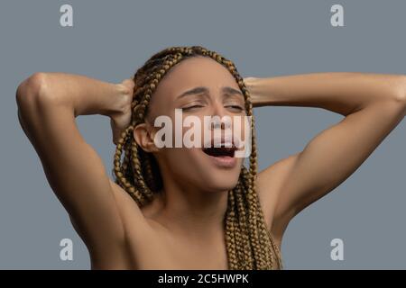 Devastated young African American holding her hands on the nape, screaming with pain Stock Photo