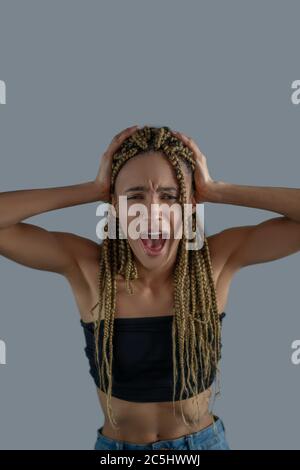 Devastated young African American holding her head in hands, screaming Stock Photo
