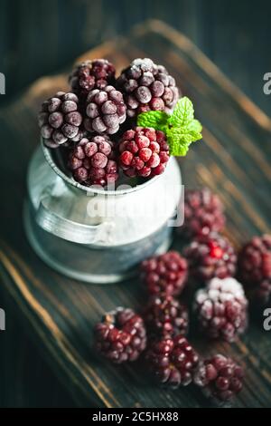 Frozen blackberries on a wooden table. Vertical. Stock Photo