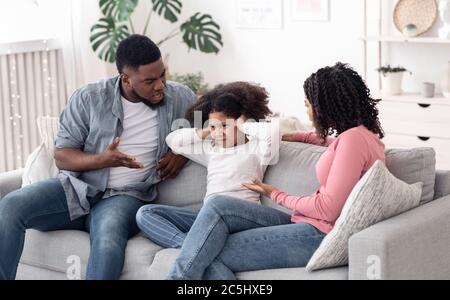 Annoyed Black Parents Scolding Stubborn Little Daughter At Home Stock Photo