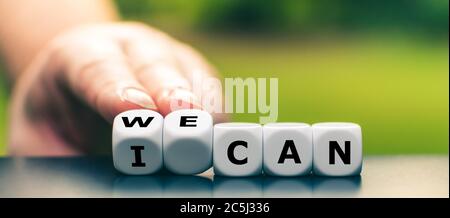 Hand turns dice and changes the expression 'I can' to 'we can'. Stock Photo