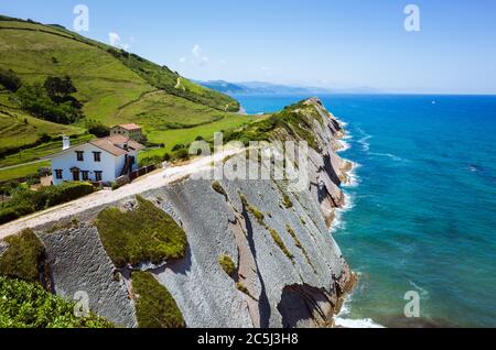 Zumaia, Gipuzkoa, Basque Country, Spain - July 15th, 2019 : Country house atop the cliff made of flysch rock over Itzurun beach. Stock Photo
