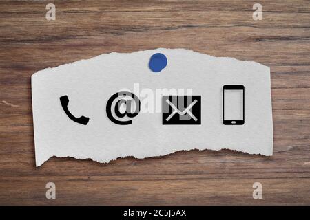 CONTACT US Icons on post it on wood table. Concept of business or customer service. Stock Photo