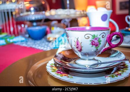 Colorful Tea party with table laid out fancy tea cups and saucers, with sweet and savory foods on platters Stock Photo