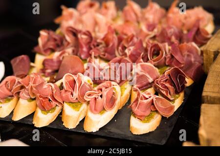 Canapes sandwiches with jamon and sauce. Plate with delicious meat bruschettas. Catering food concept Stock Photo