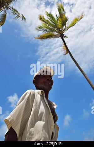 Pingwe, Zanzibar - October 6, 2019: Portrait of the old local fisherman, blue sky and palms tree on background. Tanzania, Africa Stock Photo