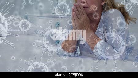 Covid-19 cells against senior woman praying Stock Photo