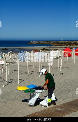 3rd July 2020, Vila Praia de Ancora, northern Portugal: A local government worker puts out bin bags on the beach in preparation for the start of the tourist season. Stock Photo