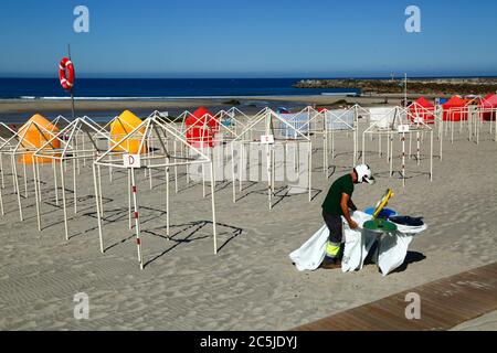 3rd July 2020, Vila Praia de Ancora, northern Portugal: A local government worker puts out bin bags on the beach in preparation for the start of the tourist season. Stock Photo