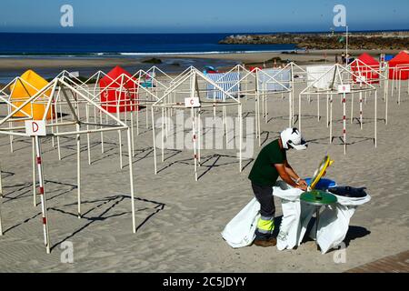 3rd July 2020, Vila Praia de Ancora, northern Portugal: A local government worker puts out bin bags on the beach in preparation for the start of the tourist season. Stock Photo