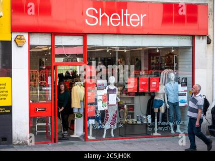 Member of staff sweeping up in doorway of the Shelter charity shop in Western Road Brighton UK Stock Photo