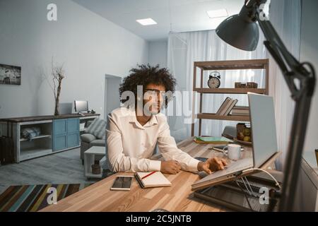 Creative man works laptop at home office interior. Copywriter or designer workplace. Overtime concept. Freelance concept. Tinted image Stock Photo