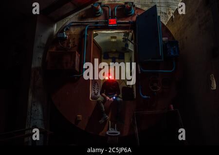 Creepy masked man in gateway corridor of airlock of abandoned bunker Stock Photo