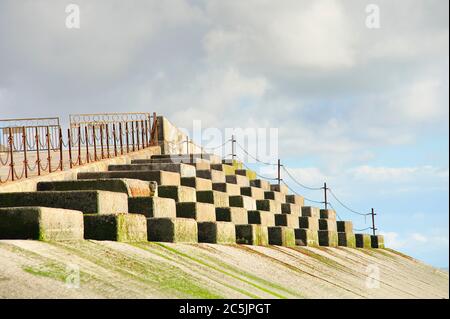 Old seawall with gates and rusty chain link fence against the sky Stock Photo