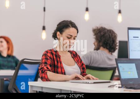 A casually dressed employee performing daily activities while working on a pc. Stock Photo