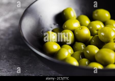 Nocellara green olives in bowl on rustic table, Apulia region Stock Photo