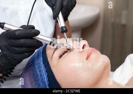 The beautician performs the microcurrent procedure in the beauty salon. The procedure stimulates collagen production, lifting, fights wrinkles, facial Stock Photo