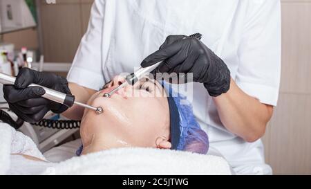 The beautician performs the microcurrent procedure in the beauty salon. The procedure stimulates collagen production, lifting, fights wrinkles, facial Stock Photo