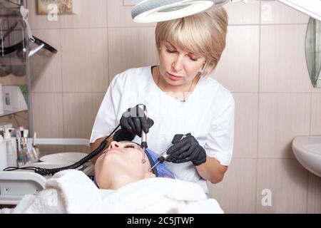 The beautician performs the microcurrent procedure in the beauty salon. The procedure stimulates collagen production, lifting, fights wrinkles, facial Stock Photo