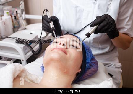 The beautician performs the microcurrent procedure in the beauty salon. The procedure stimulates collagen production, lifting, fights wrinkles, facial Stock Photo