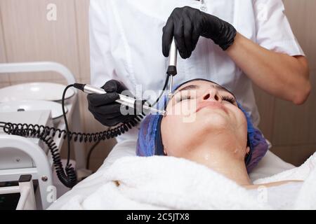 The beautician performs the microcurrent procedure in the beauty salon. The procedure stimulates collagen production, lifting, fights wrinkles, facial Stock Photo