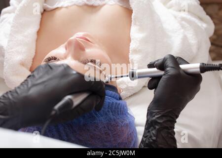 The beautician performs the microcurrent procedure in the beauty salon. The procedure stimulates collagen production, lifting, fights wrinkles, facial Stock Photo